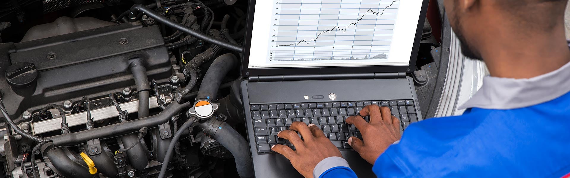 technician on laptop checking data from engine banner